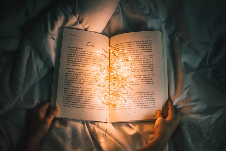 An open book with string lights inside.